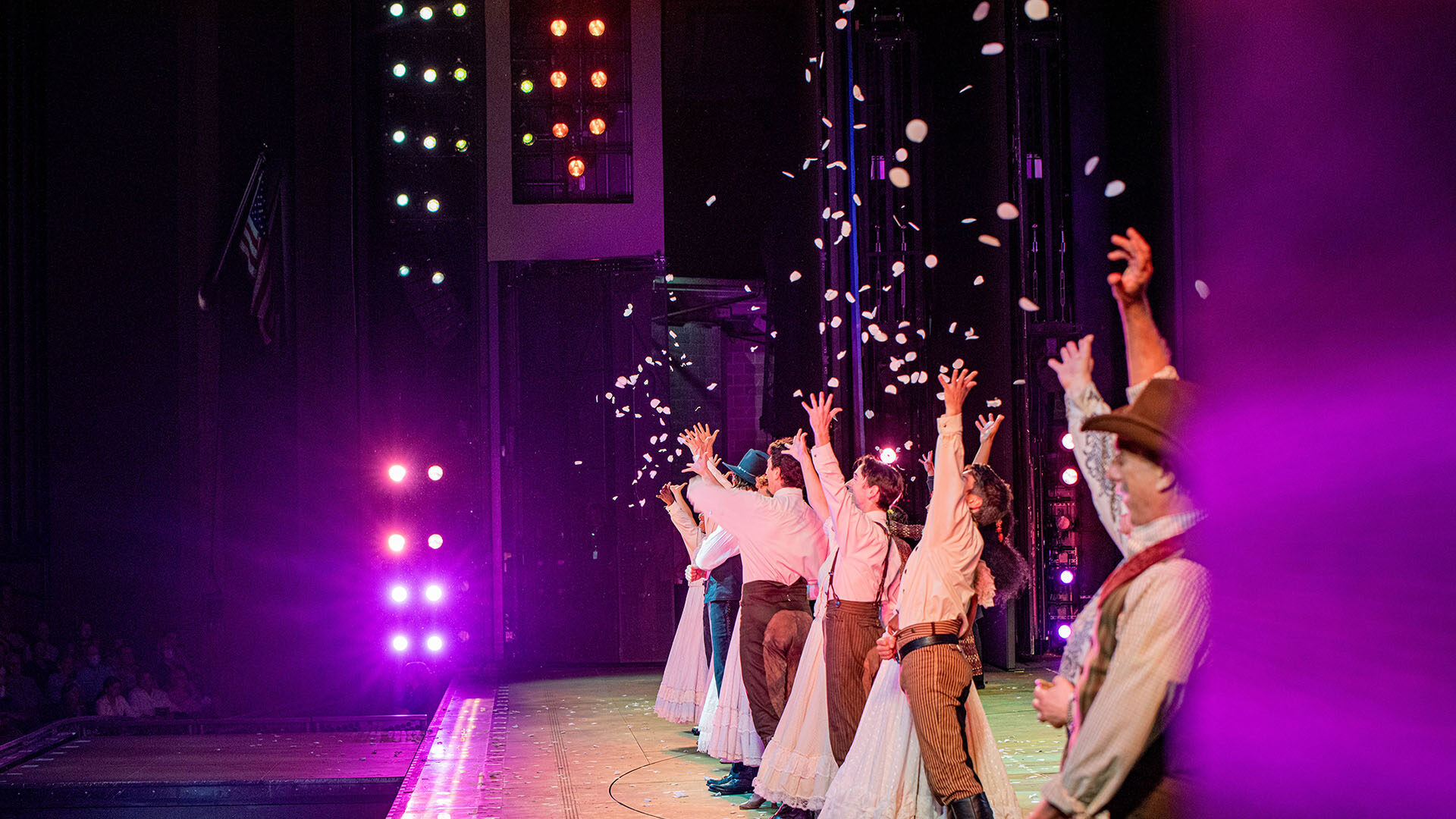 A group of actors throw confetti on the James S. McDonnell Muny stage