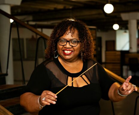 Sheilah Walker conducting while smiling at the camera