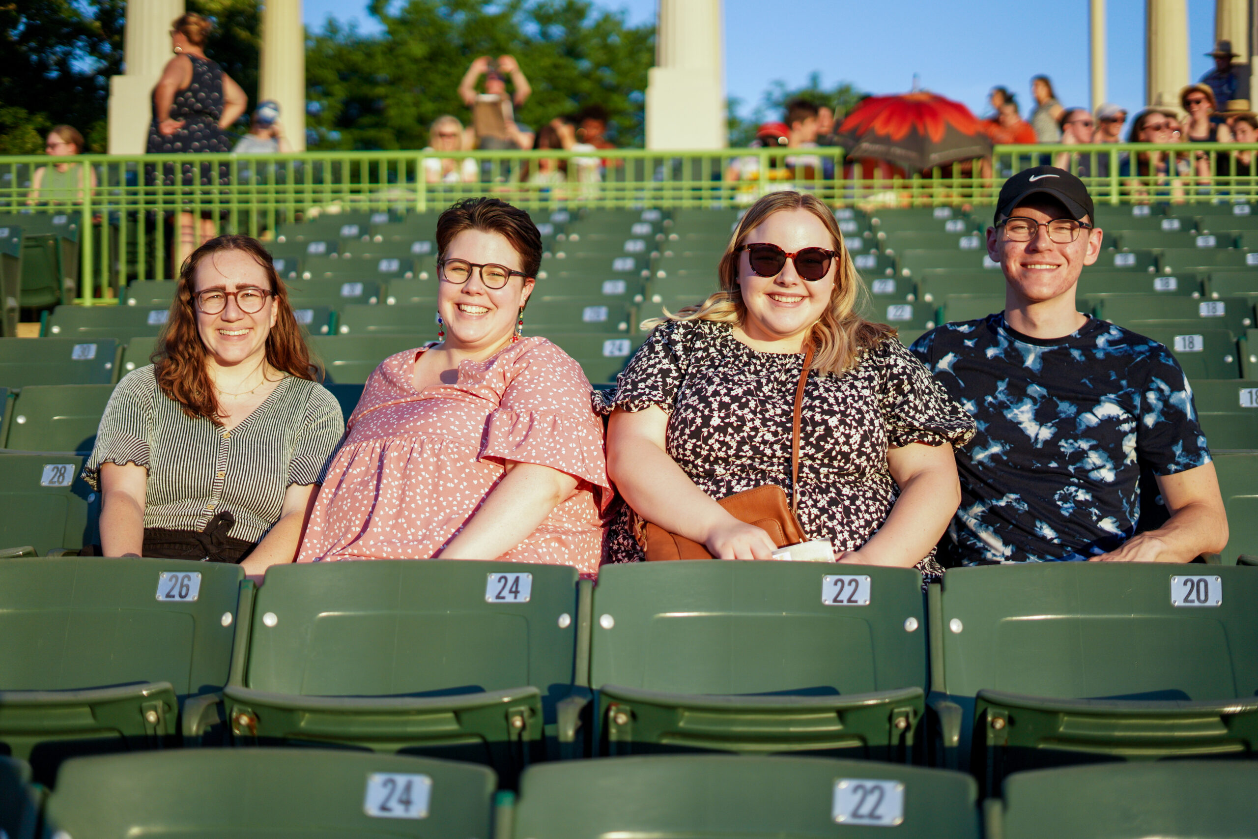 three women and one man sit in their seats smiling before a show