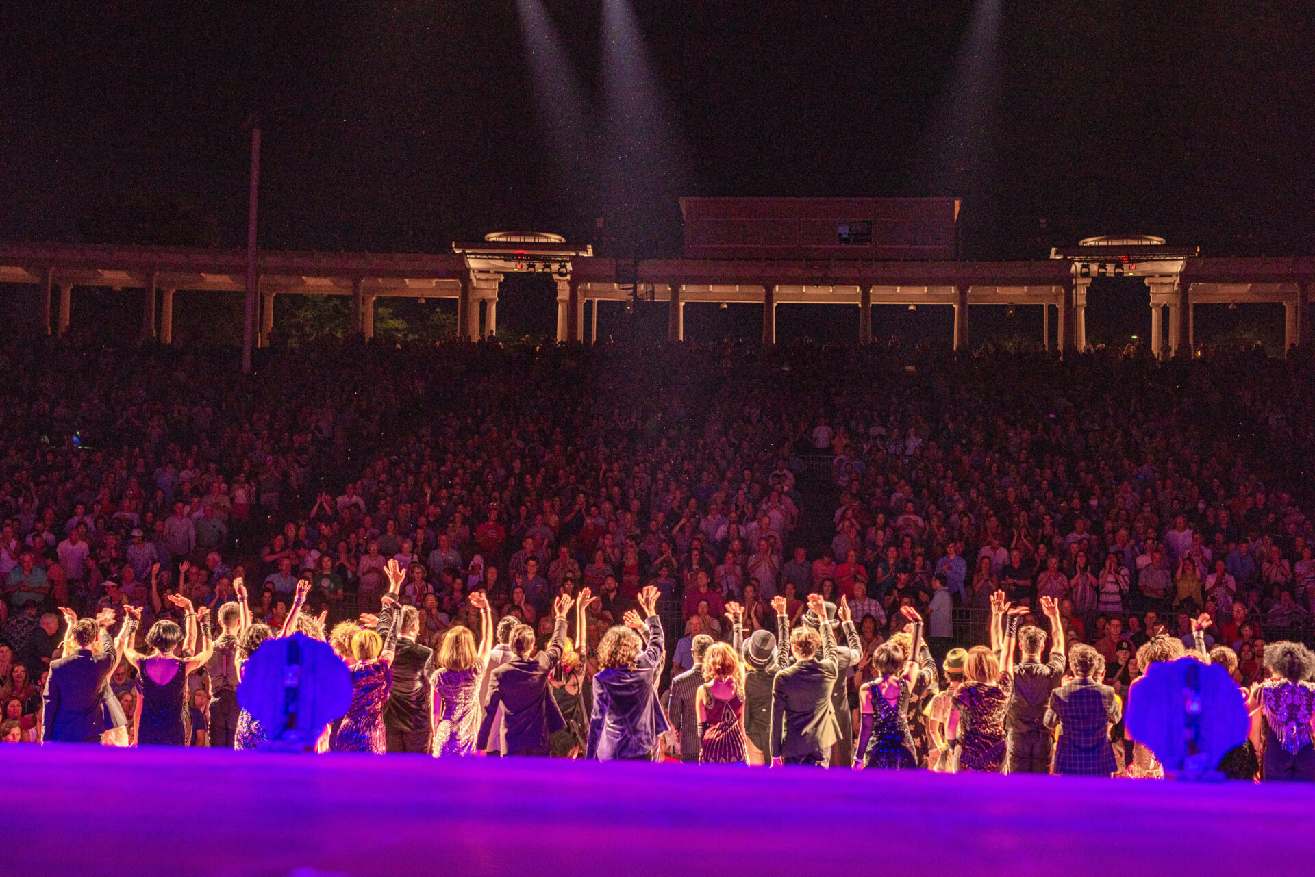 cast from behind waving goodbye to the crowd as they overlook the audience