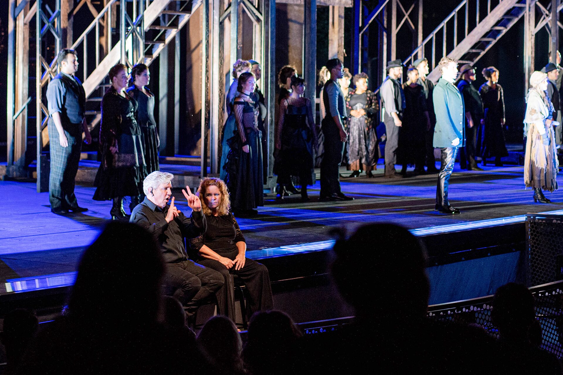 Two American Sign Language interpreters sign from the front of the Muny stage during a performance of "Les Miserables"