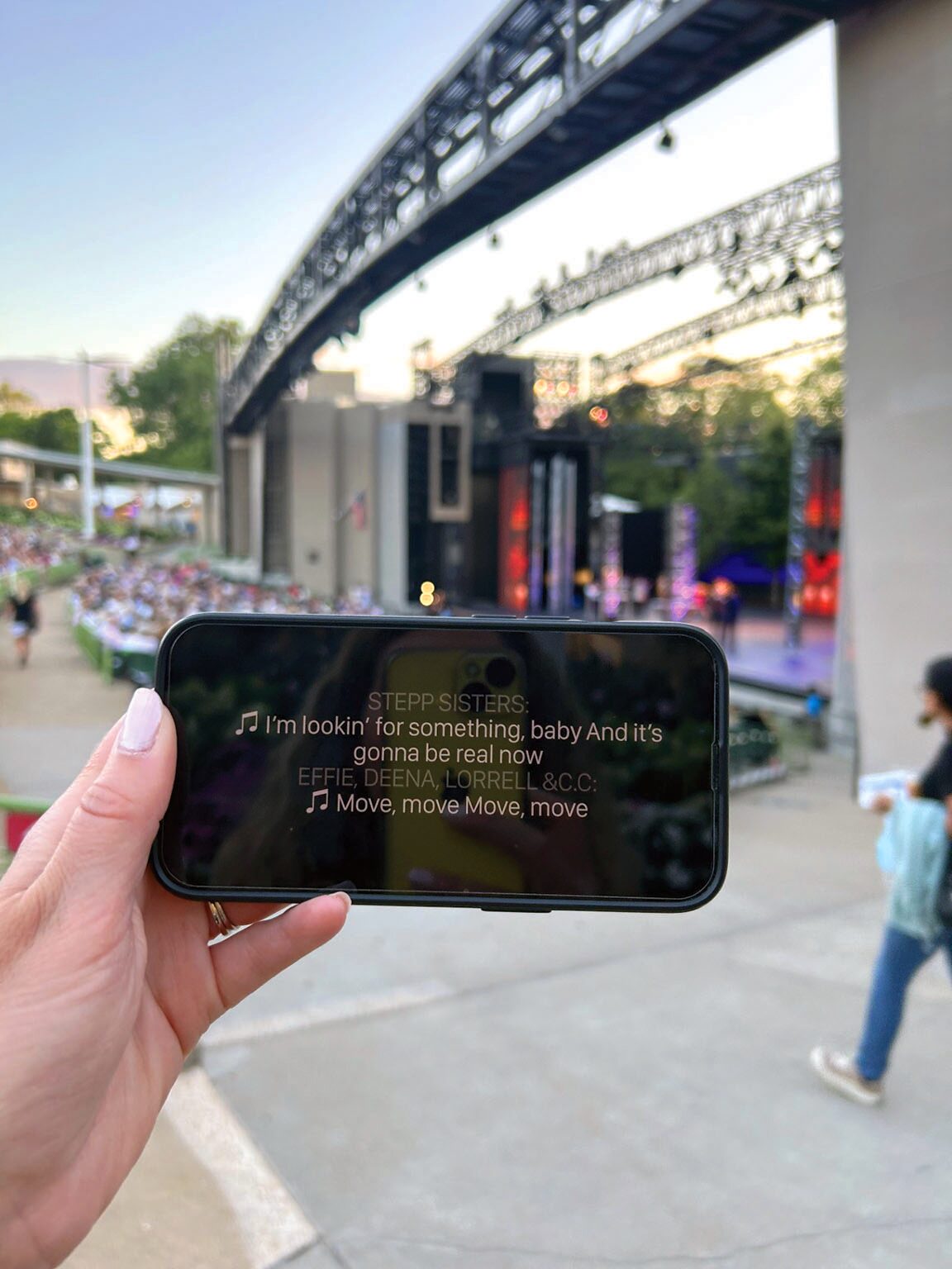 A smartphone demonstrating live closed captioning during a Muny performance