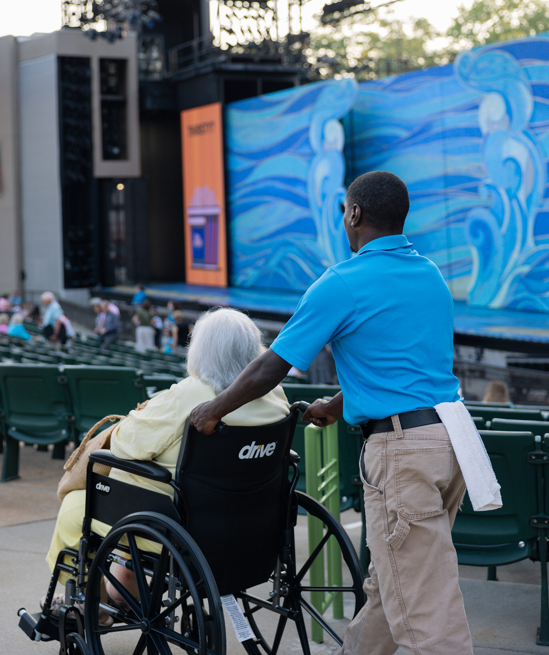 A wheelchair attendant assists a Muny patron by pushing her chair through the theatre to her seat